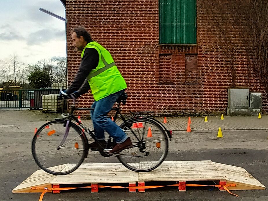 Rückenübung Auf dem Bild wird Anhand von 2 Paletten und 2 Auffahrrampen eine Baustellenbrücke simuliert, wie sie häufig bei Erdarbeiten zur Verlegung von Infrastruktur unter Radwegen verwendet werde. Martin Kamps, Radfahrtrainer im ADFC-Münsterland, wie eine Baustellenbrücke auf Radwegen befahren werden sollte.